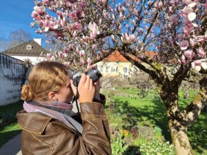 Junge Frau fotografiert mit ihrer Kamera eine Magnolie ©Bienhaus